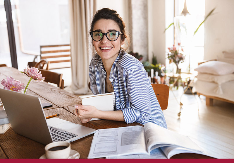 Image of cute young woman 20s in casual clothing typing on laptop while working or studying at home